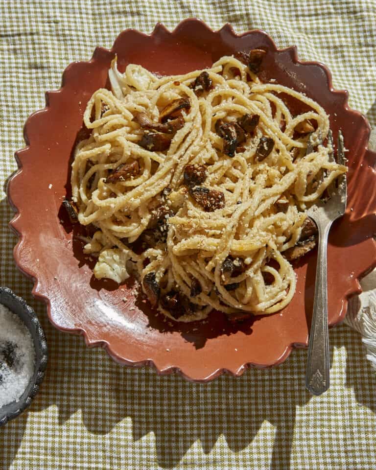 a bowl of vegan mushroom carbonara spaghetti on a checked table cloth